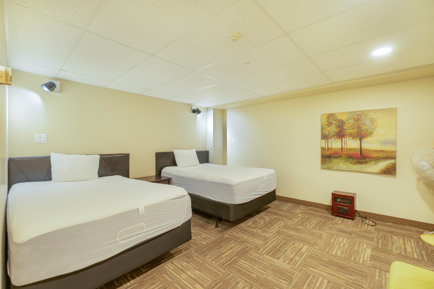 Two twin beds with white linens, a beige wall, and a landscape painting on the wall. Two twin beds with white linens, a beige wall, and a landscape painting on the wall.