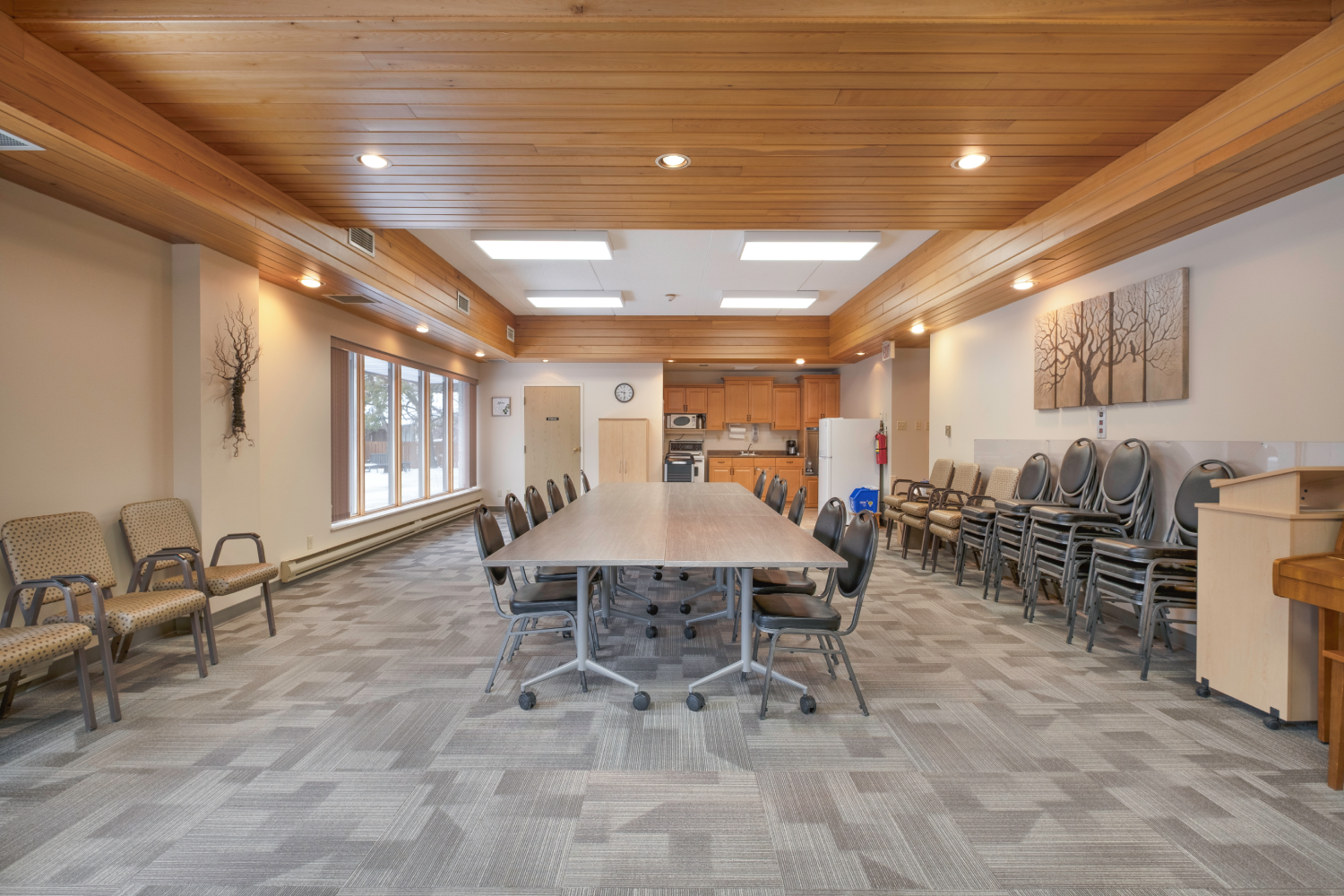Large community room with a long table, chairs, and additional seating. Large community room with a long table, chairs, and additional seating.